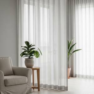 A serene space featuring a floor-to-ceiling sheer curtain acting as a soft room divider, allowing diffused natural light to pass through while creating a sense of separation and privacy.