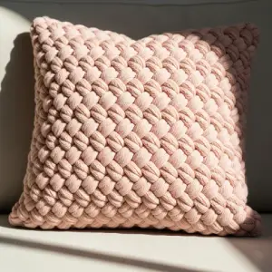 Close-up of a soft, woven blush pink cushion on a neutral sofa, bathed in warm natural light, representing subtle elegance in pastel home decor trends.