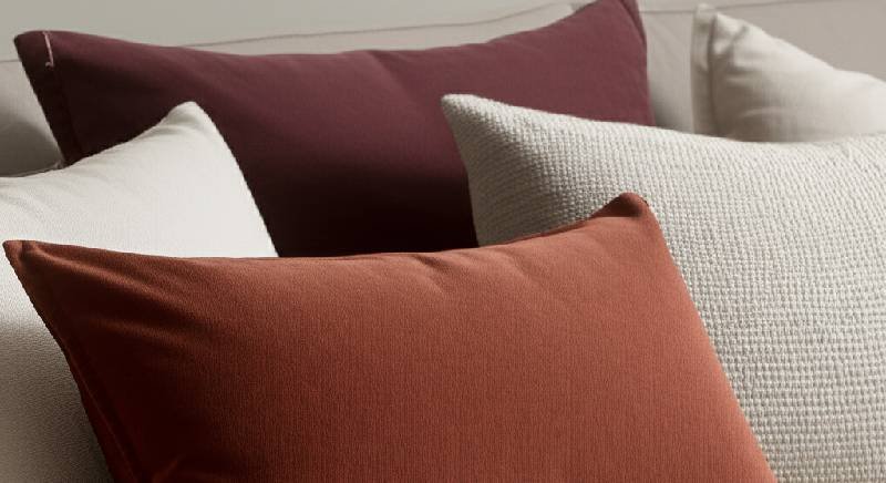 A close-up of a sofa with decorative cushion covers in rich textures like velvet and linen, showcasing an affordable way to refresh home decor.