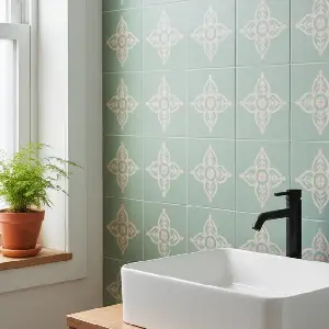 Close-up of bathroom tiles painted with a tile paint kit. The tiles have a stenciled pattern in a light color, showcasing a budget-friendly update for a modern bathroom.
